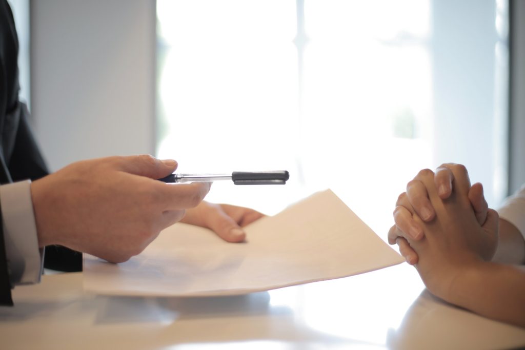 Un homme d'affaires remet un contrat à une femme pour qu'elle le signe
